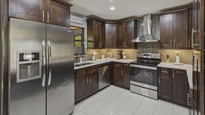 Una cucina moderna con elettrodomestici in acciaio inossidabile, pensili in legno scuro e zoccolo rivestito in piastrelle.