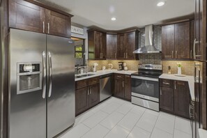 A modern kitchen with stainless steel appliances, dark wooden cabinets, and a tiled backsplash. - Wonderful 3-bedroom house in charming Lantana, less than 5 minutes from beach (Lantana)