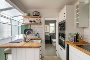 Una cocina compacta con mostrador de madera, un lavamanos, una estufa y una ventana.