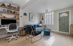 Una habitación con escritorio, silla, sofá y estantería.
