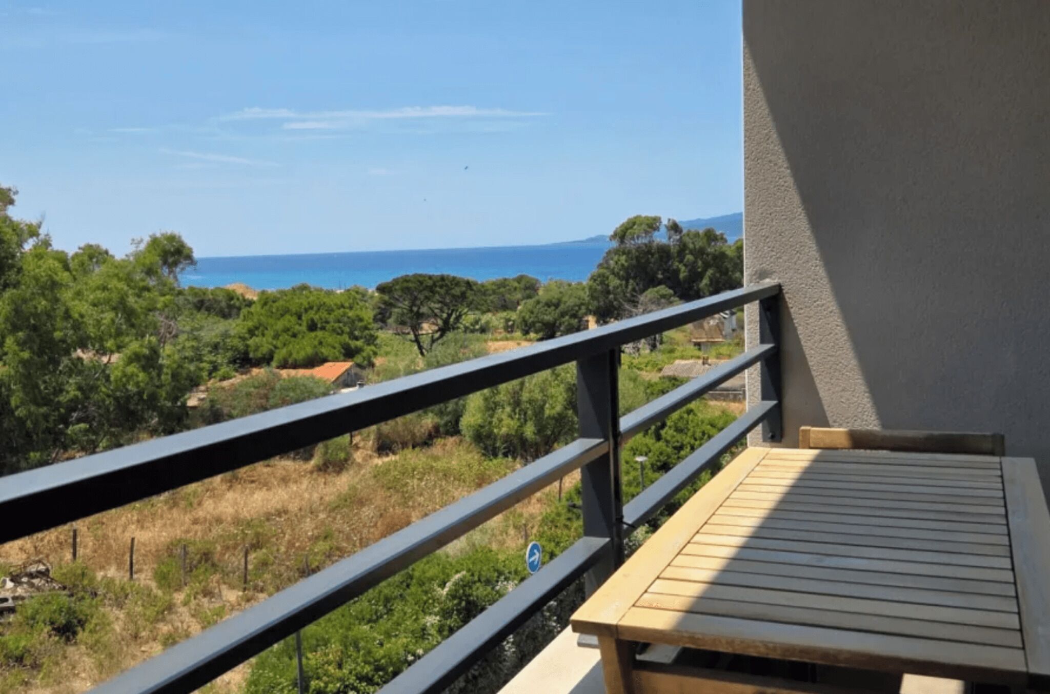 Un balcon avec vue sur la mer et la verdure.