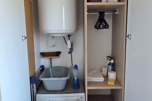 Ein Waschbereich mit Waschmaschine, Wäscheständer, Spüle und Ablage für Reinigungsmittel.