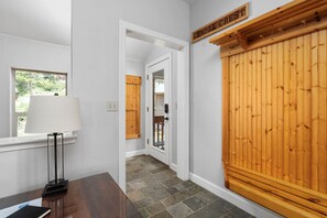 A hallway with a wooden door labeled 'CANDAL CREEST,' a window with a lamp, and a stone-tiled floor. - Candal Crest in Tamarack (Big Creek)