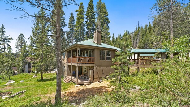 A two-story cabin with a balcony, surrounded by dense forest. - Candal Crest in Tamarack (Big Creek)