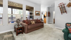 A living room with a brown sofa, a globe on a side table, and a wooden ladder on the wall. - Candal Crest in Tamarack (Big Creek)