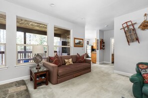 A living room with a brown sofa, a globe on a side table, and a wooden ladder on the wall. - Candal Crest in Tamarack (Big Creek)