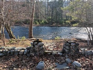 Ein Fluss mit einer Steinmauer und Bäumen im Hintergrund.