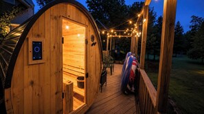A wooden sauna with a door, a control panel, and a bench inside.