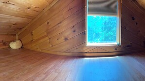 Un intérieur en bois avec une lucarne, un plafond incurvé et une fenêtre visible.