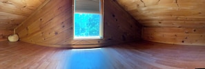A wooden interior with a skylight, curved ceiling, and a visible window.