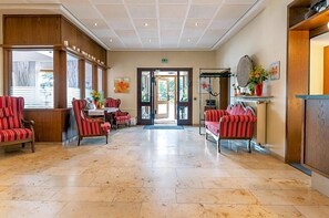 A lobby with striped chairs, a reception desk, and a large door leading outside. - Alte Post (Krefeld)