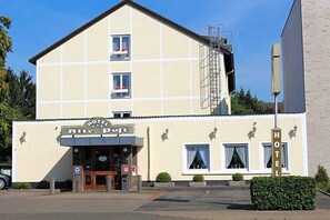 A hotel with a beige facade, a signboard, a staircase, and a parking area. - Alte Post (Krefeld)