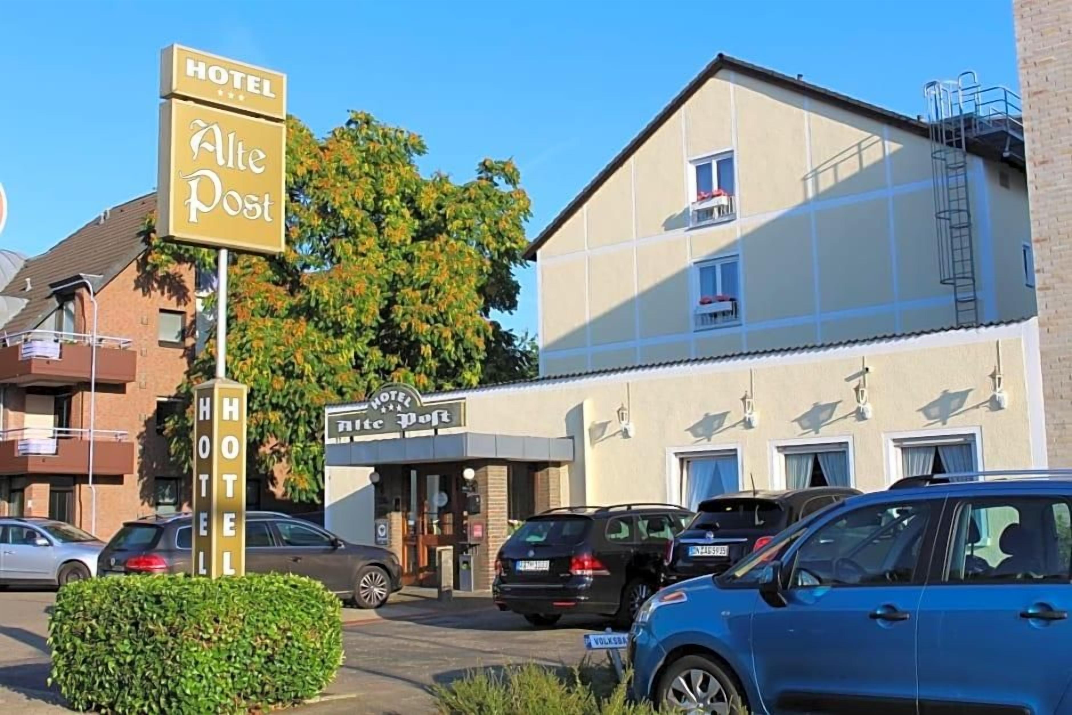 Ein Hotel namens 'Hotel Alte Post' mit einer Schilderfassade, einem Hauseingang und abgestellten Autos.
