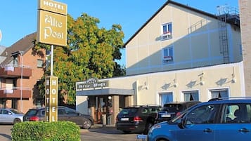 Ein Hotel namens 'Hotel Alte Post' mit einer Schilderfassade, einem Hauseingang und abgestellten Autos.