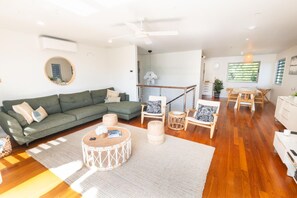 Ein modernes Wohnzimmer mit einem grünen Sofa, einem runden Couchtisch und Holzsesseln.
