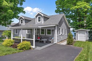 Ein zweistöckiges Haus mit überdachter Veranda, Garage und Auffahrt.