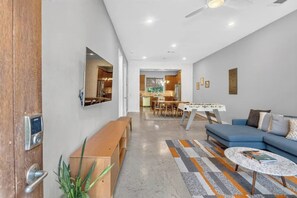 A modern living room with a sofa, a coffee table, and a dining area with a table and chairs. - Barton Springs Oasis Close to Downtown  3BR w deck (Austin)
