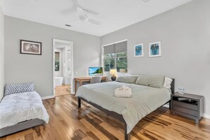 A bedroom with a bed, bedside tables, a desk, a chair, a ceiling fan, and a window with a view. - Barton Springs Oasis Close to Downtown  3BR w deck (Austin)