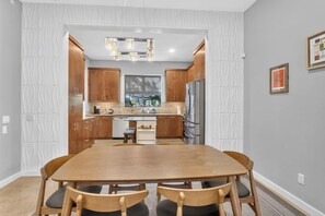 A modern kitchen with wooden cabinets, a central island, and a dining area with a wooden table and chairs. - Barton Springs Oasis Close to Downtown  3BR w deck (Austin)