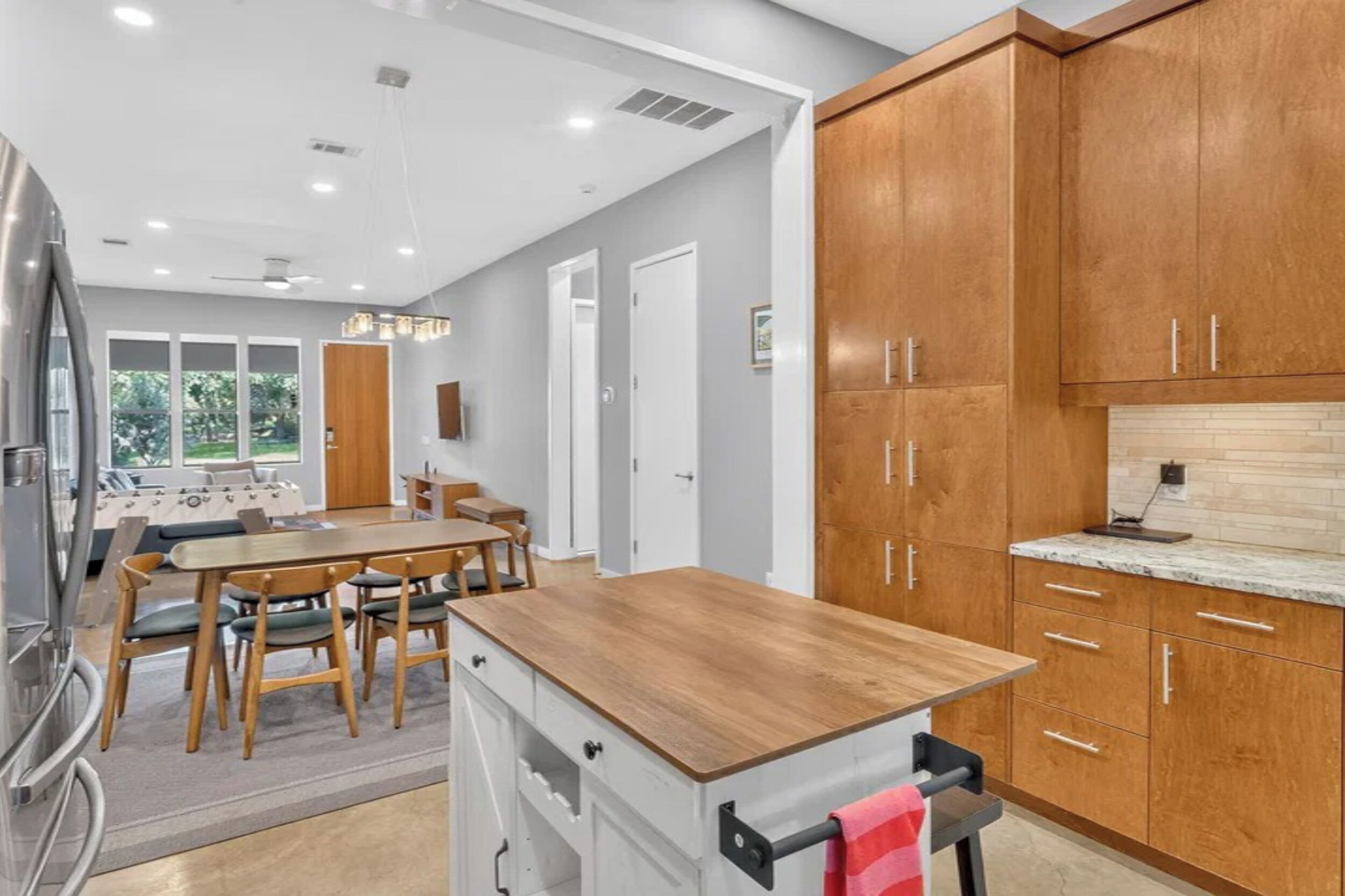 Una cocina moderna con gabinetes de madera, encimera de madera y un comedor con mesa y sillas.