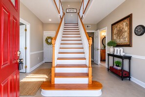 A staircase with a wooden handrail, a red door, a white door, a wall-mounted clock, and a framed picture. - Tranquil 4-bedroom house with beautiful views in charming Lancaster (Lancaster)
