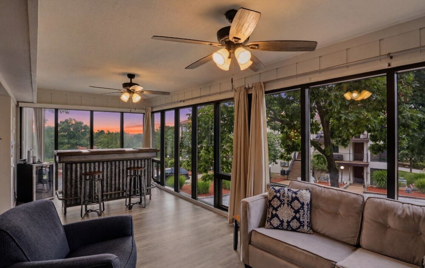 A spacious room with a bar area, a sofa, and a ceiling fan.