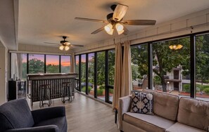 A spacious room with a bar area, a sofa, and a ceiling fan. - The Lake Effect - Multiple Pools & Central Location! (Lake Ozark)