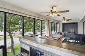 A modern kitchen with large windows, a bar area, and ceiling fans. - The Lake Effect - Multiple Pools & Central Location! (Lake Ozark)