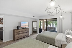 A bedroom with a TV, wooden dresser, bed, and a view through a glass door. - The Lake Effect - Multiple Pools & Central Location! (Lake Ozark)