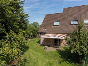Ein Haus mit geneigtem Dach, Ziegelaußenwand und überdachter Terrasse.