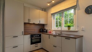 Una cucina moderna con forno integrato, lavello e finestra vista su piante.