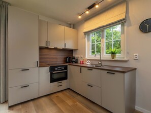 Eine moderne Küche mit Einbauofen, Spüle und Fenster mit Blick ins Grüne.
