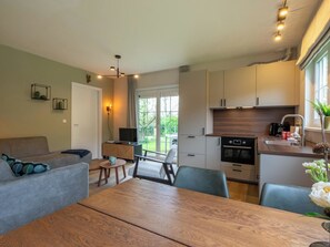 Eine moderne Küche mit Essbereich, Fernseher und Blick ins Freie.