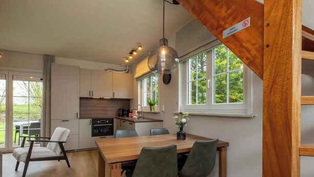 Una cucina moderna con un tavolo da pranzo in legno, sedie e una lampada a sospensione.