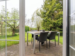 Eine Außenpatio mit Tisch und Stühlen, umgeben von viel Grün und Bäumen.