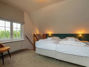 Ein Schlafzimmer mit zwei Betten, einem Sessel, einem Fenster und einer Treppe.