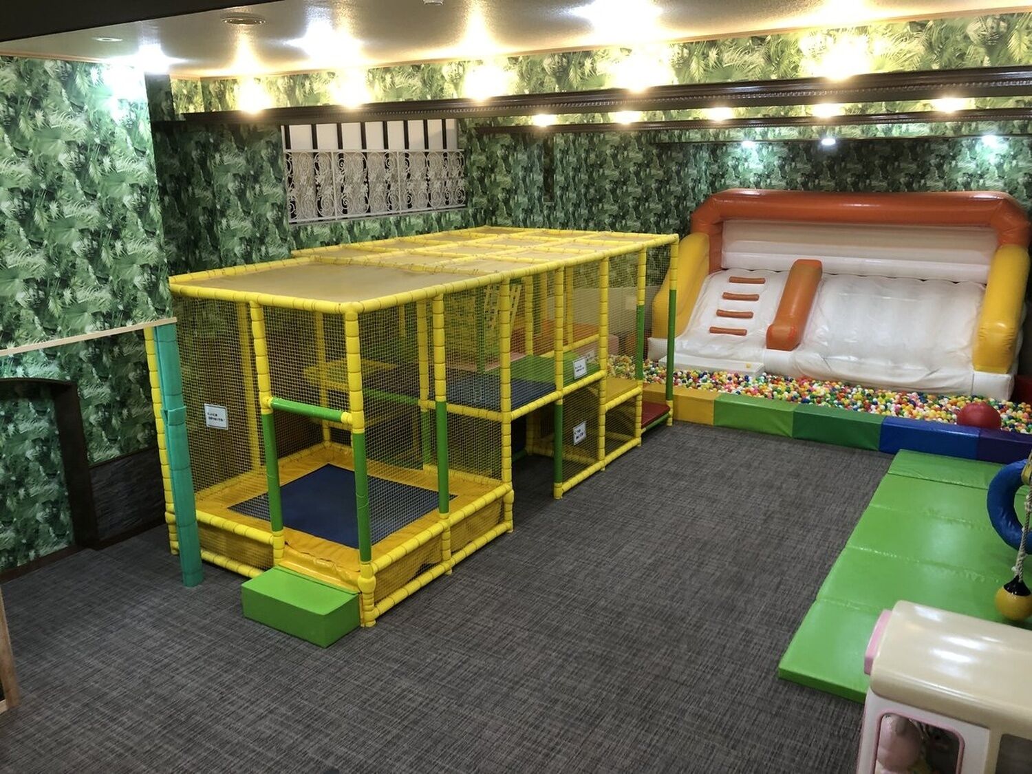 A play area with a trampoline, a climbing structure, and a ball pit.