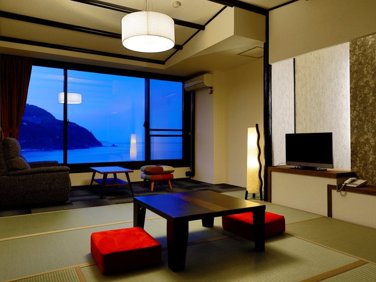 Una habitación con un ventanal grande, un televisor de pantalla plana, una mesa y un sofá.