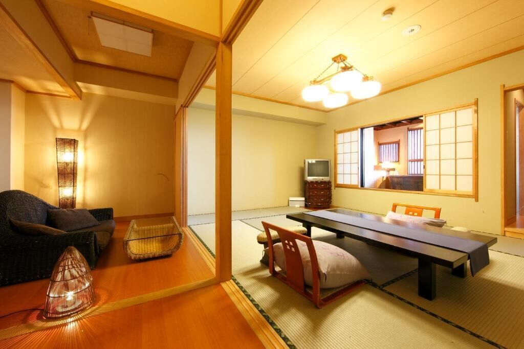 Una habitación japonesa tradicional con suelo de tatami, una mesa baja, un sofá y una televisión.