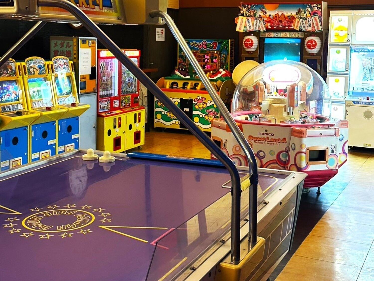 A variety of arcade games and a purple table tennis table in an indoor setting.