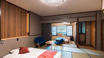 Habitación de hotel con cama, dos sillas, una mesita y vistas al mar a través de amplios ventanales, además de una puerta corredera que da al baño.