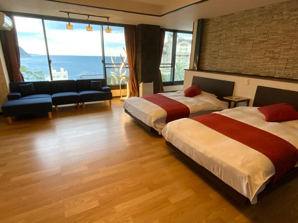 Una habitación de hotel moderna con una cama grande, un sofá y vista al océano.