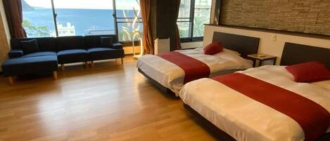 A modern hotel room with a large bed, a sofa, and a view of the ocean.