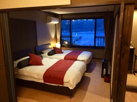Habitación de hotel con dos camas, una ventana con vista al mar y un equipo de aire acondicionado.