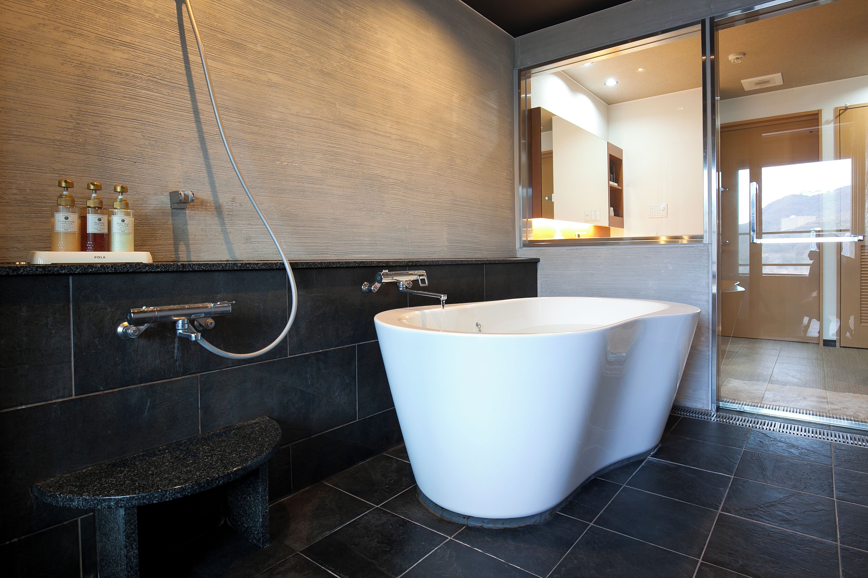 Un baño moderno con una bañera independiente, un banco y una zona de ducha.
