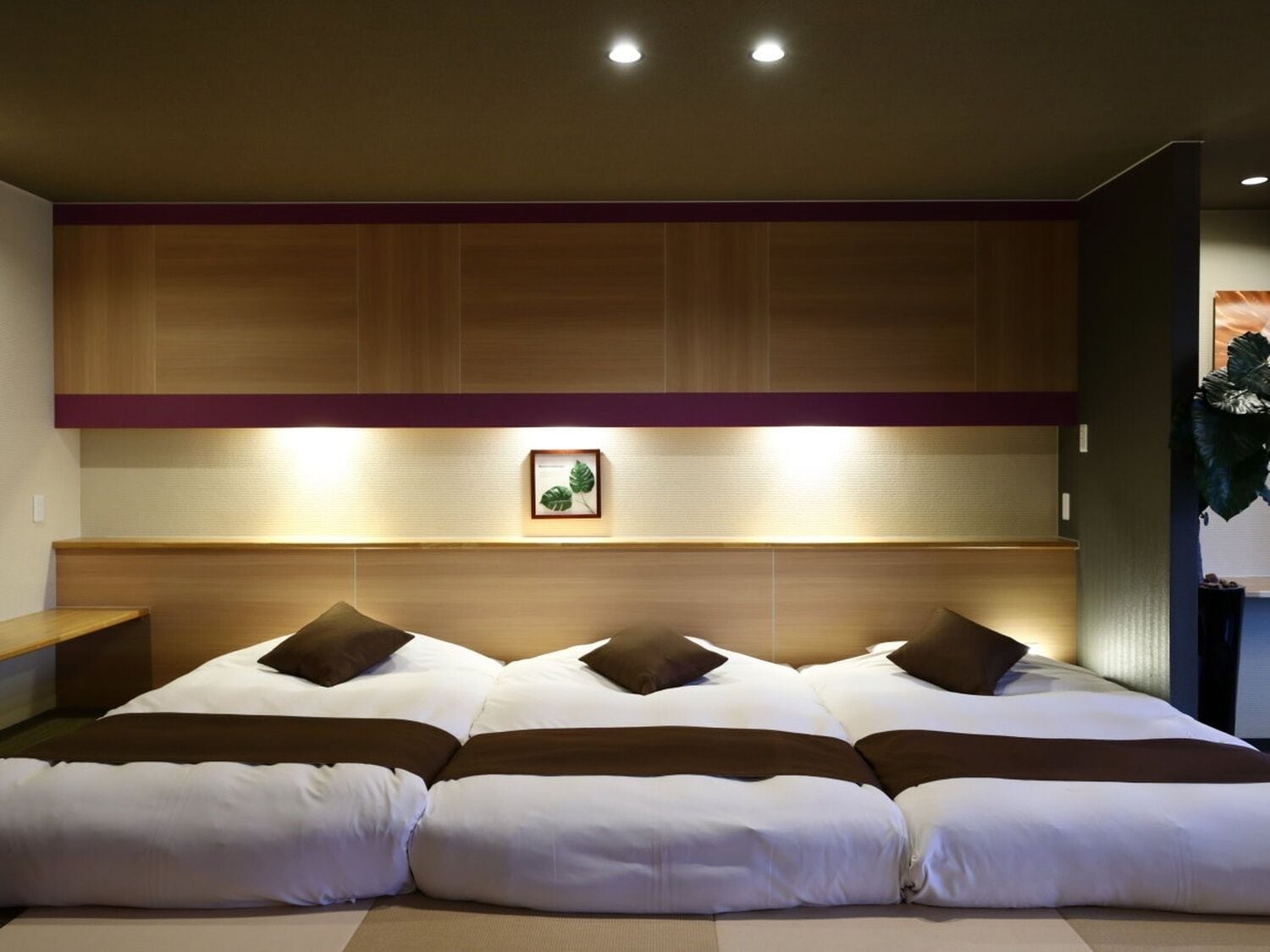A hotel room with a large bed, wooden headboard, and a framed botanical illustration.