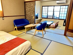 A hotel room with tatami flooring, a bed, a sofa, a table, and a TV.