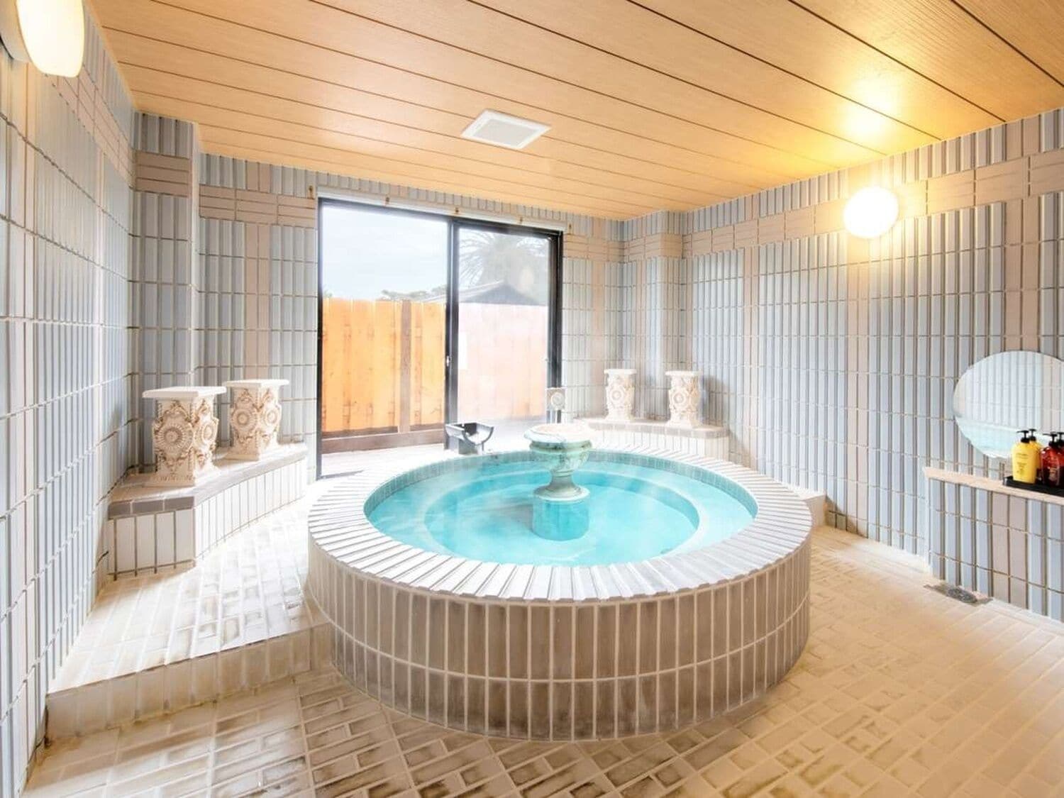 A spa area with a hot tub, tiled walls, and a wooden ceiling.