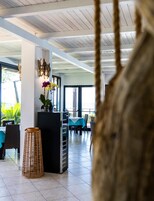 Un comedor interior con techo alto, una barra negra central y vistas al exterior.