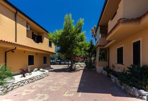 A courtyard with buildings, a paved walkway, and a tree. - Villaggio Riviera Calabra (Zambrone)